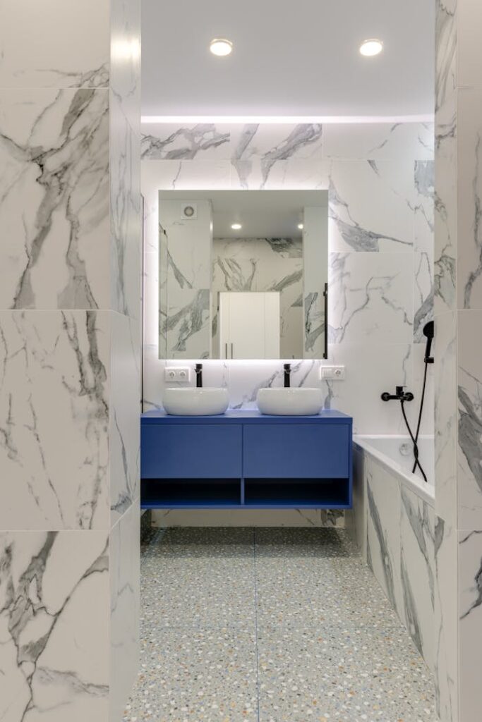 Stylish marble bathroom with blue vanity and double sinks.